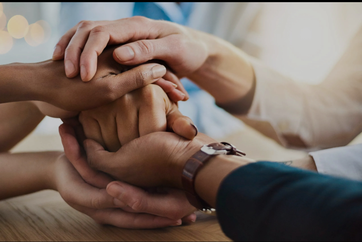 Caregivers and family holding hands in support